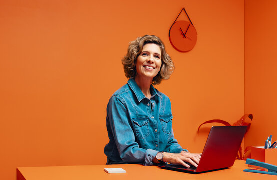Female manager typing on laptop in monochromatic office space