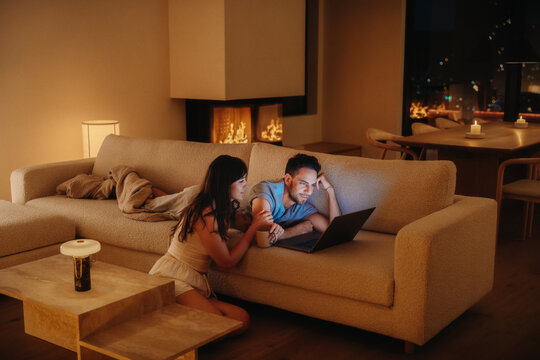 Cozy evening at home with couple using laptop by fireplace