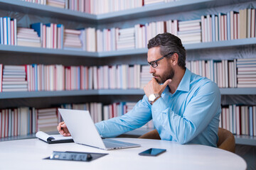 Obraz premium Portrait of teacher with book in library classroom. Handsome teacher in university library. Teachers Day. Teacher giving classes. School teacher in library. Tutor at college library on bookshelf.