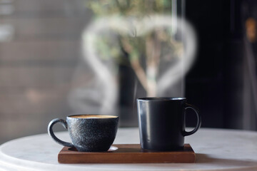 Coffee cup with smoke in heart shape placed on wooden table in coffee shop. Love concept.