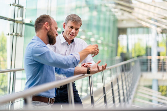 Colleagues discussing innovative business solutions leaning standing in office corridor