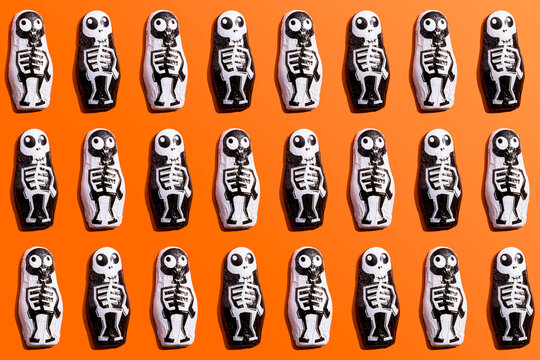 Pattern of rows of Halloween candy with skeleton wrapping against orange background