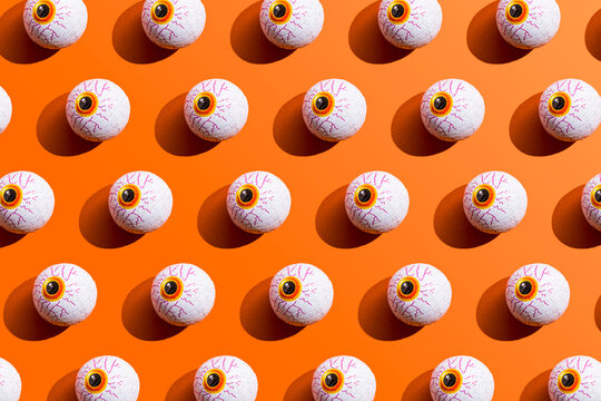 Pattern of rows of Halloween candy with eyeball wrapping against orange background