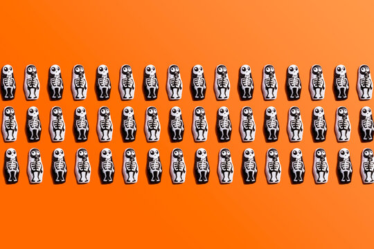 Pattern of rows of Halloween candy with skeleton wrapping against orange background