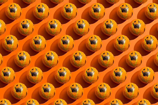 Pattern of rows of Halloween candy with jack o lantern wrapping against orange background