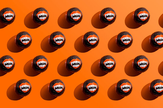 Pattern of rows of Halloween candy with vampire teeth wrapping against orange background