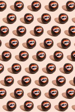 Pattern of rows of Halloween candy with vampire teeth wrapping against beige background