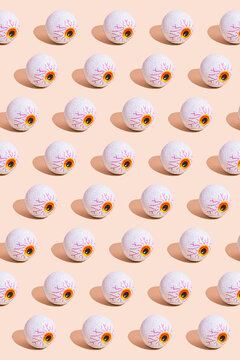 Pattern of rows of Halloween candy with eyeball wrapping against beige background