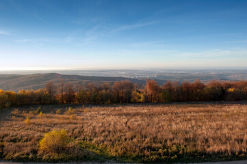 Fototapeta premium A scenic view of mountain peaks under the sun on a forest ridge on a mountainside with golden aspens and bright autumn colors creating a virtual color palette.