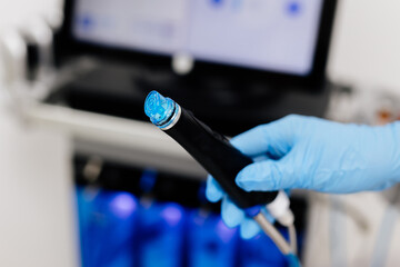 A cosmetologist sets up a HydraFacial device in a modern spa clinic, getting ready for an advanced...