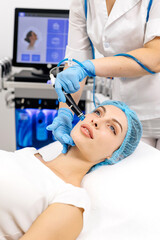 Naklejka premium A cosmetologist wearing gloves performs vacuum cleaning and polishing of the facial skin of a middle-aged woman in a cosmetology clinic. Professional moisturizing and rejuvenating hardware procedures.