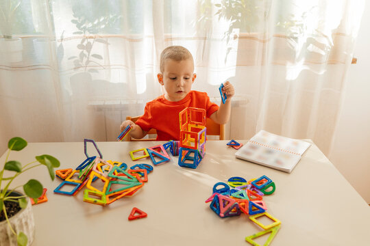 Boy stacking magnetic blocks on table at home