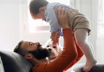 Smiling father picking up baby boy at home