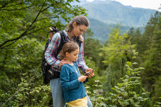 Mother and daughter using compass and hiking in forest