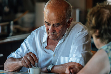 Family life of a senior couple at home drinking coffee