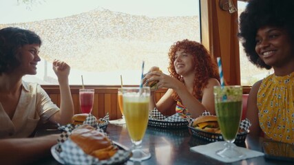 Cinematic footage about a group of multi-ethnic friends eating and having fun in an american styled diner restaurant. Drinking colored fruit milkshakes.