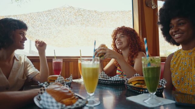 Cinematic footage about a group of multi-ethnic friends eating and having fun in an american styled diner restaurant. Drinking colored fruit milkshakes.