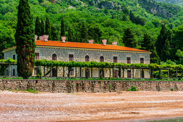 panoramic view from adriatic sea bay to a beach and beautiful palace of Oman hotel in Budva, Montenegro with green garden and mountains