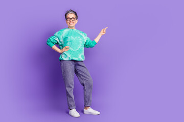 Full body photo of attractive senior woman point empty space dressed stylish green clothes isolated on purple color background