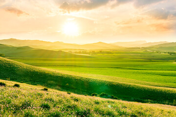 beautiful rural landscape of green spring or summer season valley with flowering green hills and meadow and nice scenic sunset on background