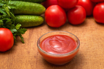 Bowl with tasty ketchup and fresh vegetables in kitchen