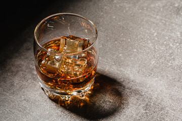 Glass of whiskey with ice on a light background