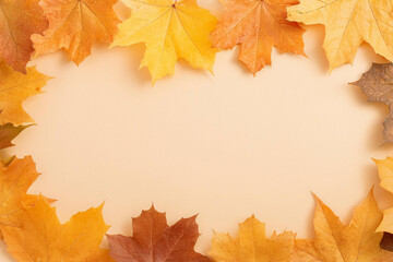 Autumn Maple leaves frame on pastel beige