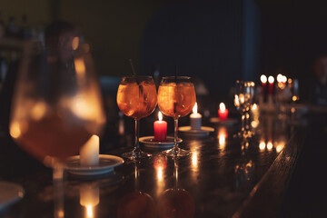 Holidays composition made of glass of aperol shpritz and candles on a dark background. Preparation...