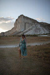 Naklejka premium A woman plus size dressed in a dress walking against the background of a white mountain. Beautiful girl with a long hair developing in the wind travels