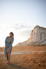 Naklejka premium A woman plus size dressed in a dress walking against the background of a white mountain. Beautiful girl with a long hair developing in the wind travels