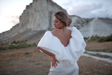 A woman plus size dressed in a dress walking against the background of a white mountain. Beautiful girl with a long hair developing in the wind travels