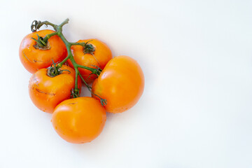 several yellow tomatoes on a white background with a shadow