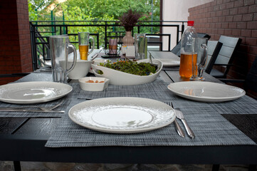 There is food on a wooden table. Have dinner outside. Summer salad with arugula, tomatoes.