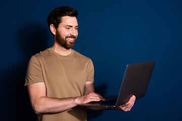 Photo of mature age senior it specialist programmer brunet man with laptop working remote isolated on dark blue color background