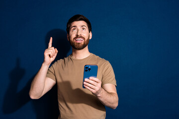 Photo of guy brunet hair model in beige t shirt using smartphone direct finger above follow channel isolated on dark blue color background