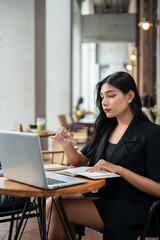 Fototapeta premium An attractive Asian businesswoman is focusing on reading report on her laptop, working remotely.