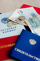 A certificate, a diploma and a work book are lie next to Russian money. Vertical photo.