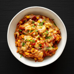 Homemade One-Pot Cheesy Taco Pasta in a Bowl on a black background, top view. Flat lay, overhead,...