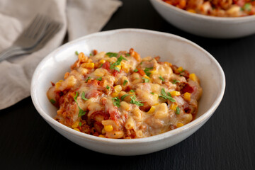 Homemade One-Pot Cheesy Taco Pasta in a Bowl on a black background, side view.