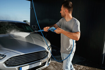 Side view, car wash, high pressure. Man is with his automobile outdoors