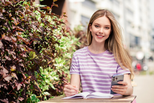 Photo of adorable sweet lady wear striped t-shirt sitting cafeteria typing modern device outdoors urban city street - Powered by Adobe