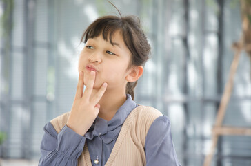 Happy smiling asian little girl looking pointing up three fingers, number 3 counting gesture