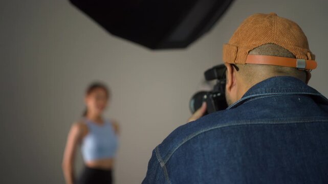 Behind shooting of Professional man photographer working shooting woman model using digital camera and flash studio in studio on white background. photography concept.
