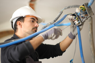 Electrician installing electrical system in a house under reform
