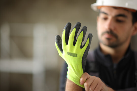Construction worker putting protective glove before work