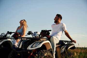 Sitting, taking a break. Man and woman are on ATV outdoors