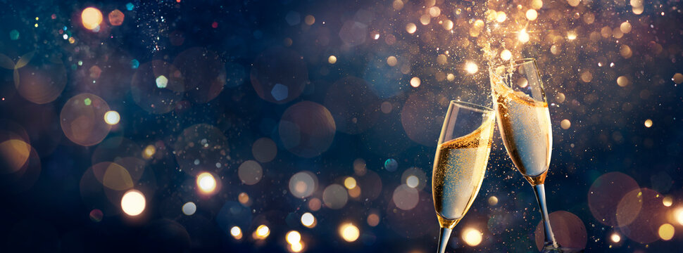Happy New Year - Champagne Toast Celebration - Goblets With Golden Glittering On Blue Abstract Background With Defocused Bokeh Lights