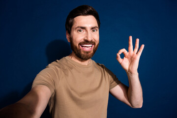 Fototapeta premium Photo portrait of young handsome guy brunet hair with stubble beard show okey isolated on dark blue color background