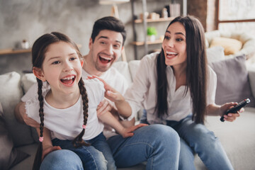 Photo of positive good mood parents child dressed casual clothes laughing watching comedy indoors house apartment room