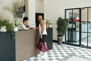 Man consulting about sport program with administrator at reception